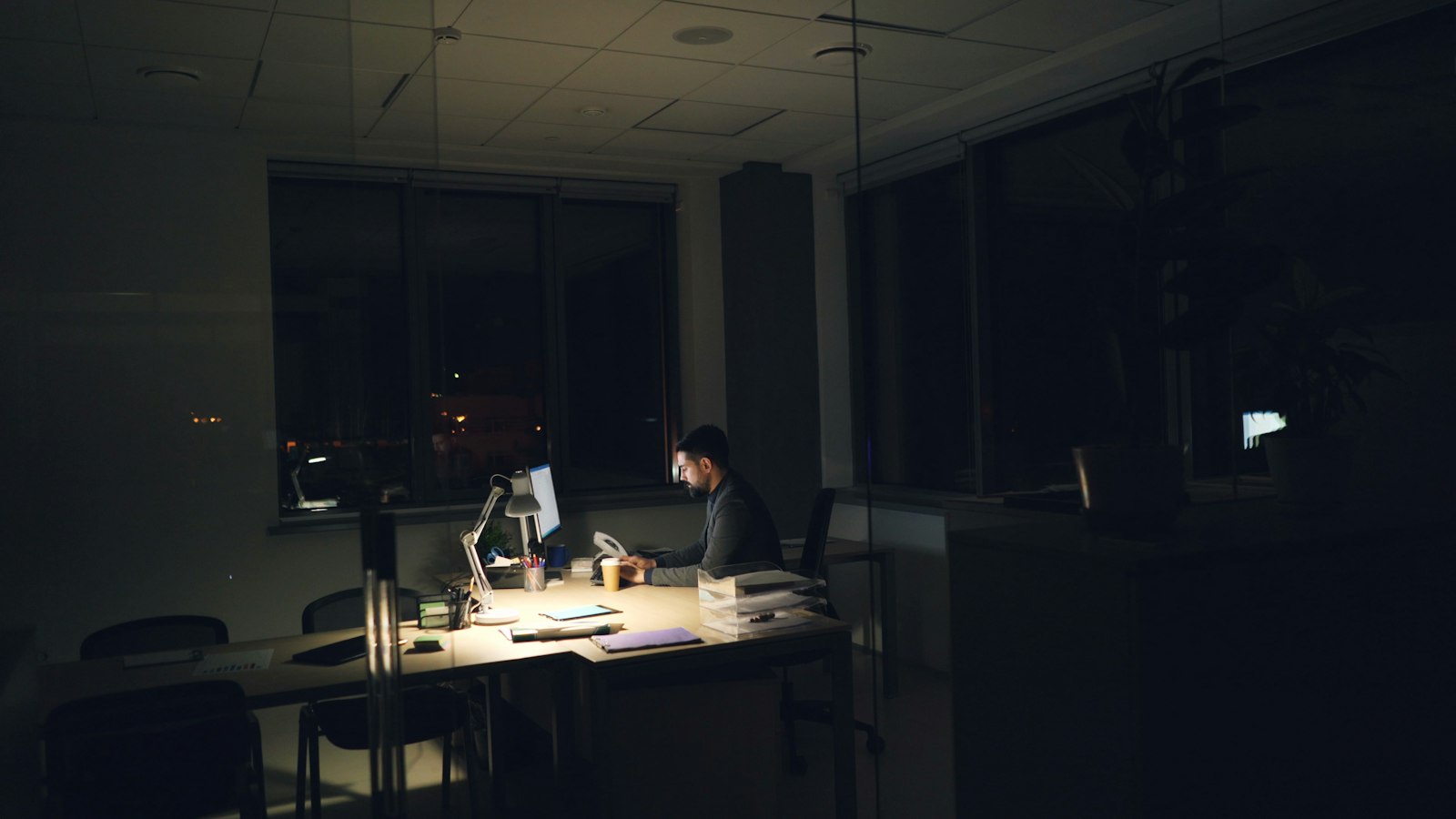 One engineer at a lit desk in a dark room, watching feeds